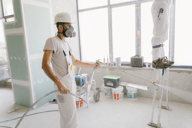 man-in-white-t-shirt-wearing-hard-hat-using-a-hose-to-wash-the-house