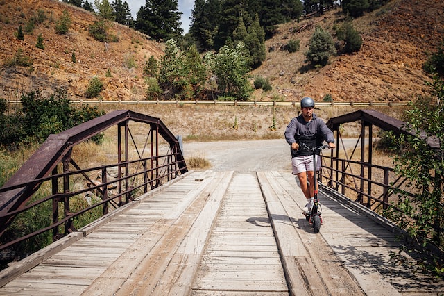 a man on an electric scooter rides on a wooden bridge