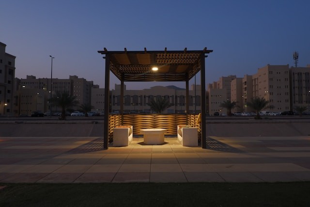 a gazebo with benches and lights in the evening
