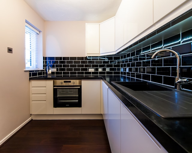 a-kitchen-with-a-black-counter-top-and-white-cabinets